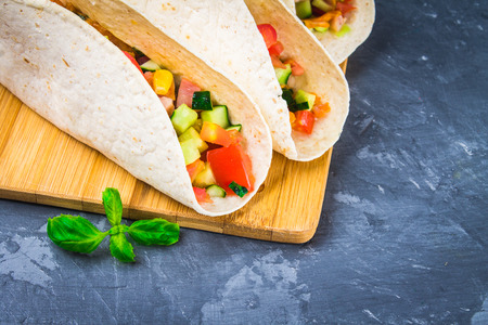 Traditional Mexican tacos with meat and vegetables on wooden backgroundの写真素材