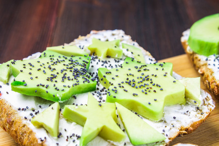 Sandwiches from bread with slices, zvezdami, hearts from avocado and curd cheese on a brown wooden background.の写真素材
