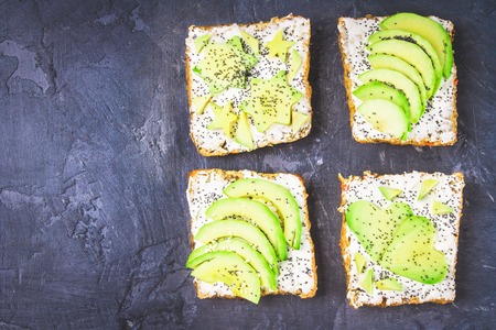 Sandwiches from bread with slices, zvezdami, hearts from avocado and curd cheese on a gray dark marble background.の写真素材