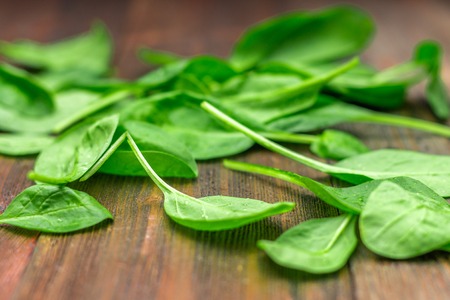 Fresh juicy spinach leaves on a wooden brown table. Natural products, greens, healthy food,...