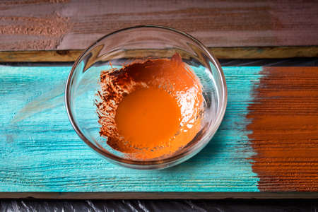 A container with brown paint and a brush on a blue board.の写真素材
