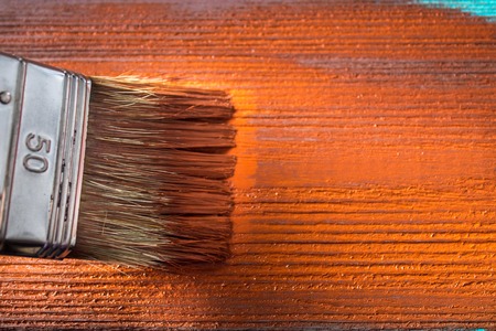 Brush with paint in hand. A man paints blue boards in a brown paint brush.の写真素材