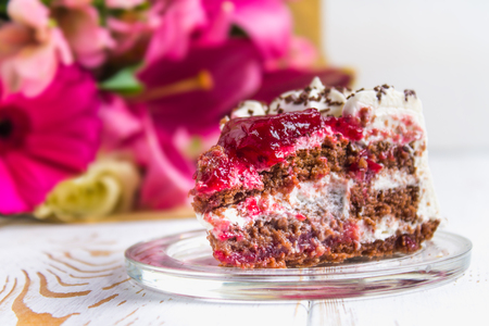 A piece of cake and a bouquet of flowers on a white wooden table. Celebrating the birthday, a gift.の写真素材