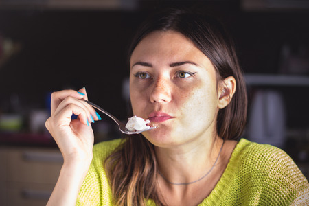 Girl eating chocolate desert brown with white creamの写真素材