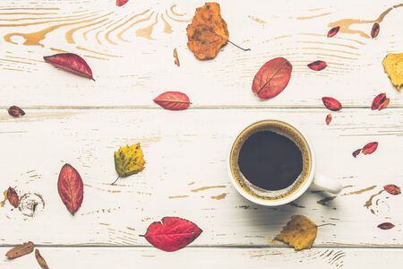 Mug of hot coffee in autumn setting on a wooden table with a knitted scarf, sweater. Comfort, warmth, cozy.の写真素材
