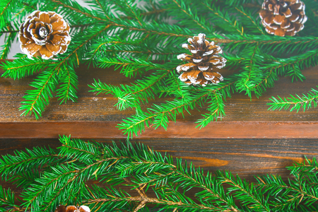 Red New Year's cones lie on a wooden brown shelf surrounded by fir branchesの写真素材