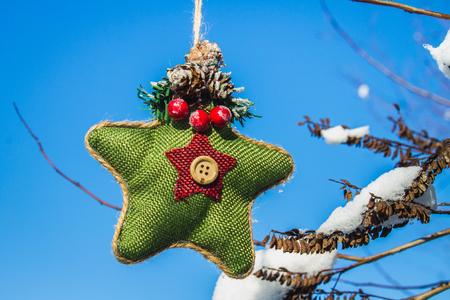 A green knitted star in Scandinavian style hangs on a branch with snow. Christmas toysの写真素材