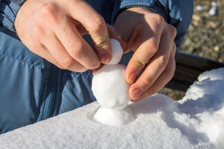 Male hands sculpting from the snow small snowballs that would make a snowmanの写真素材
