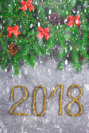 Fir branches with cones and red bows on top of a gray concrete background. New Year Christmas. Text 2018 of gold tinselの写真素材
