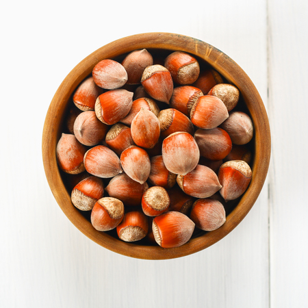 Walnut hazelnuts scattered on sackcloth on a white wooden tableの写真素材
