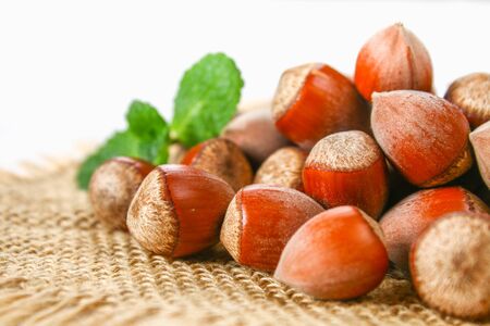 Walnut hazelnuts scattered on sackcloth on a white wooden tableの写真素材