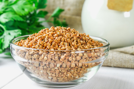 Raw buckwheat in glass bowls on sackcloth on a wooden background. Healthy diet foodの写真素材