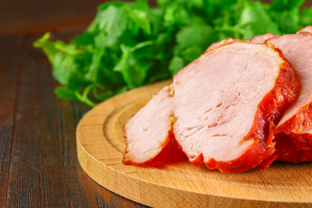 Sliced Roast Pork Loin on a brown wooden table with cilantroの写真素材