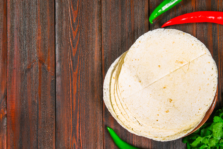 whole wheat tortillas on wooden board and vegetablesの写真素材