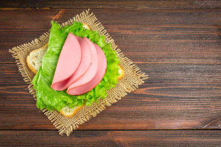 Sliced sausages with salad leaves on the wood backgroundの写真素材
