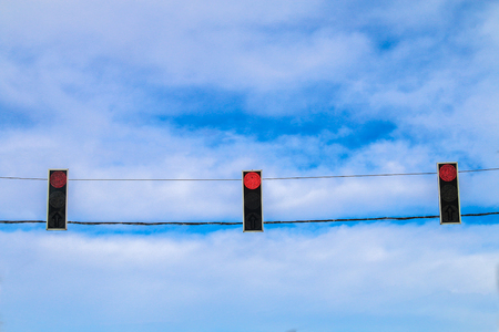 Three red traffic lights hang over the road against the blue sky. Prohibition signalの写真素材