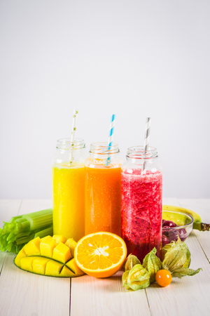 Multicolored smoothies in bottles of mango, orange, banana, celery, berries, on a wooden tableの写真素材