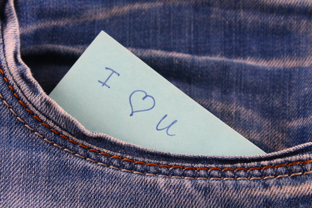 Paper note with the inscription I love you, with love peeps out of the pocket of jeans trousers. The concept of the day of lovers. St. Valentine's Dayの写真素材