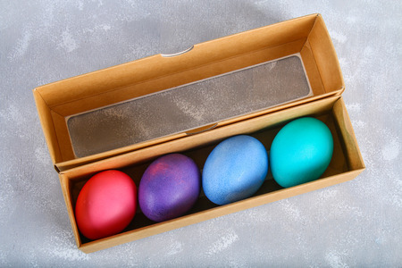 Colored Easter eggs in a gift box on a gray concrete backgroundの写真素材