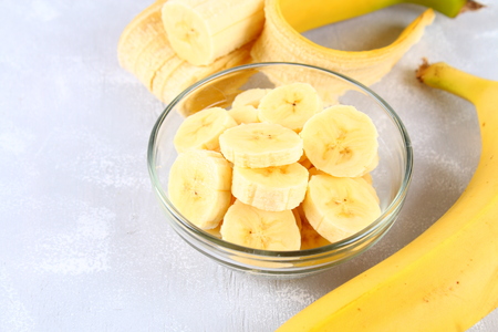 Bananas are whole and cut on a slice in a cup on a gray backgroundの写真素材