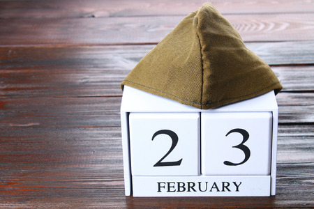 White wooden perpetual calendar with the date of February 23 on a wooden table. Defender of the Fatherland Day. Military pilot's jacketの写真素材