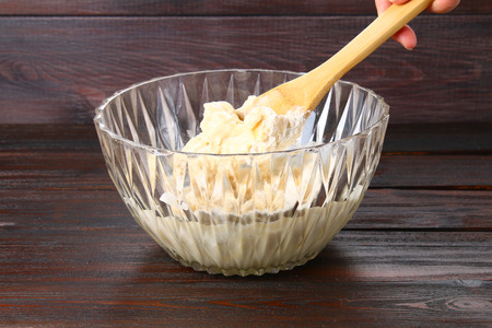 Blade in hand stirring dough for muffins on a wooden tableの写真素材