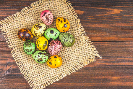 Quail multi-colored Easter eggs on a brown wooden tableの写真素材