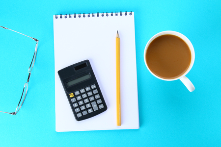 Top view image of open notebook with blank pages and coffee on blue background, ready for adding or mock up. Still life, business, office supplies or education conceptの写真素材