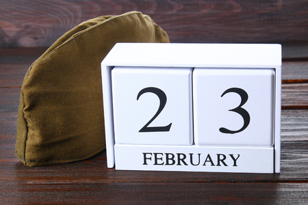 White wooden perpetual calendar with the date of February 23 on a wooden table. Defender of the Fatherland Day. Military pilot's jacketの写真素材