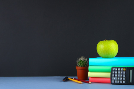 A pile of books and stationery on a chalkboard background.の写真素材