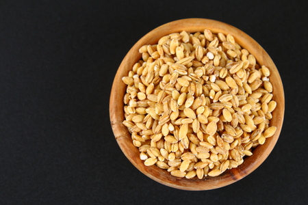 Dry pearl barley in a wooden bowl on a black chalkboardの写真素材
