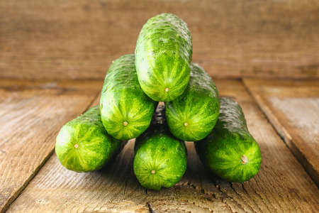 Fresh cucumbers with a leaf on an old wooden tableの写真素材