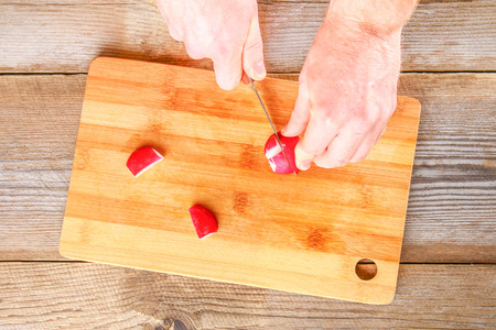 Men's hands cut the Bolognese sausage on a cutting board on an old wooden tableの写真素材