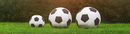 Three soccer balls stand in a row on the green grass. Sport gameの写真素材