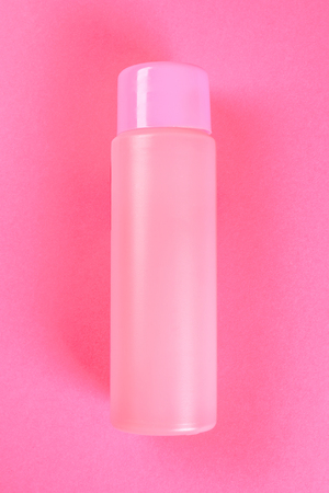 A pink bottle, a bottle for cosmetics, shampoo or food, a drink on a pink pastel background. Summer. Top view. Flat lay. Copy spaceの写真素材