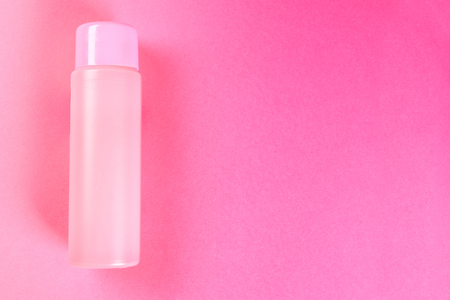 A pink bottle, a bottle for cosmetics, shampoo or food, a drink on a pink pastel background. Summer. Top view. Flat lay. Copy spaceの写真素材