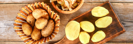 Men's hands clean potatoes for okroshki on an old wooden tableの写真素材