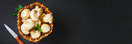 White fresh champignons with parsley on a wooden board on a gray dark table. Mushrooms. Copy the space. Top viewの写真素材