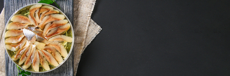 Marinated herring in oil on a wooden board on a gray dark table. Snackの写真素材