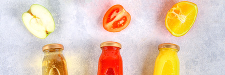 Bottles with fresh orange, apple, tomato juice on a gray concrete table. Fruits and vegetables around. Top view. Flat Layの写真素材