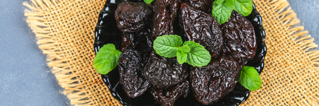 Prunes and fresh mint leaves in a bowl on a concrete tableの写真素材