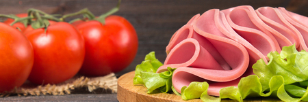 Sliced sausages with salad leaves on the wood background.の写真素材