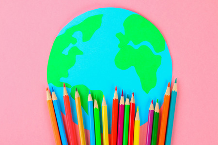 World art. Planet Earth and pencils, brushes on a pastel pink backgroundの写真素材