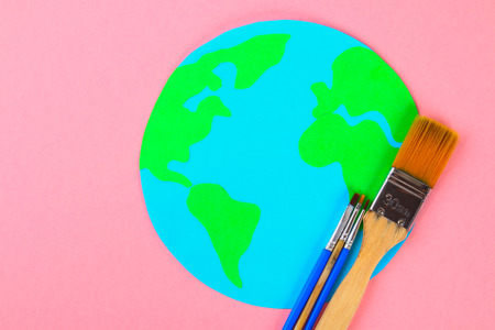 World art. Planet Earth and pencils, brushes on a pastel pink backgroundの写真素材