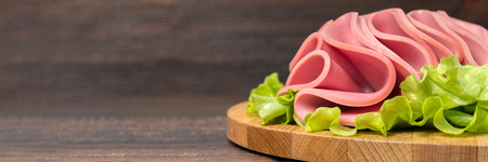 Sliced sausages with salad leaves on the wood background.の写真素材