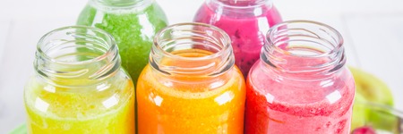 Multicolored smoothies in bottles of mango, orange, banana, celery, berries, on a wooden tableの写真素材