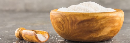 White sugar sugar in a wooden plate with a dustpan on a dark background.の写真素材