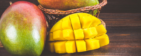 Tropical fruit mango on a wooden background, whole or slicedの写真素材