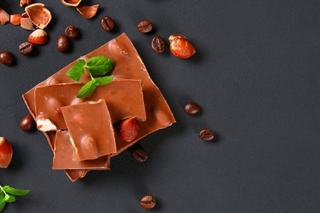 Chocolate with hazelnuts, mint and grains of coffee on a dark gray tableの写真素材