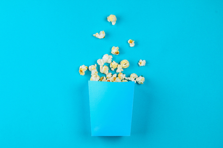 Box of popcorn spilled on blue backgroundの写真素材